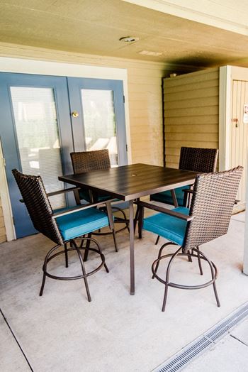 a patio with a wooden table and chairs